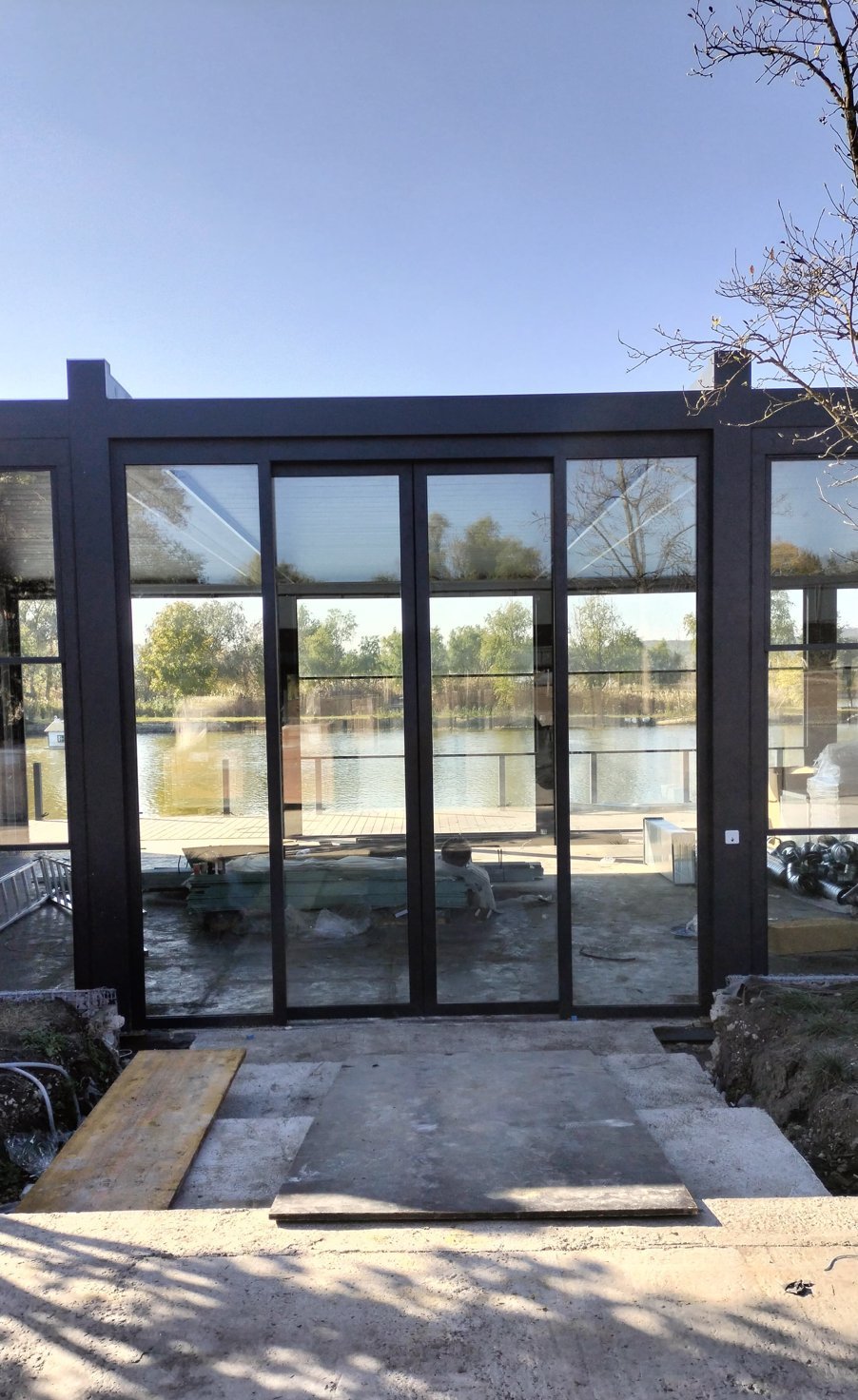 Glass entrance doors framed in dark aluminum, lake visible through the glass