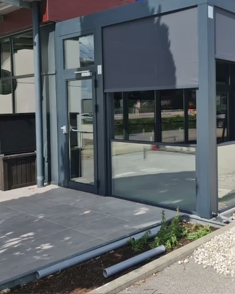 Patio enclosure with zip screens lowered and glass walls at a commercial building