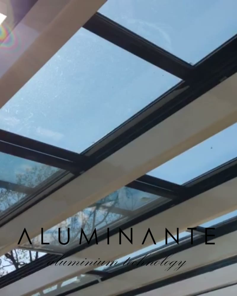 Sliding glass roof panels on aluminum beams against the sky