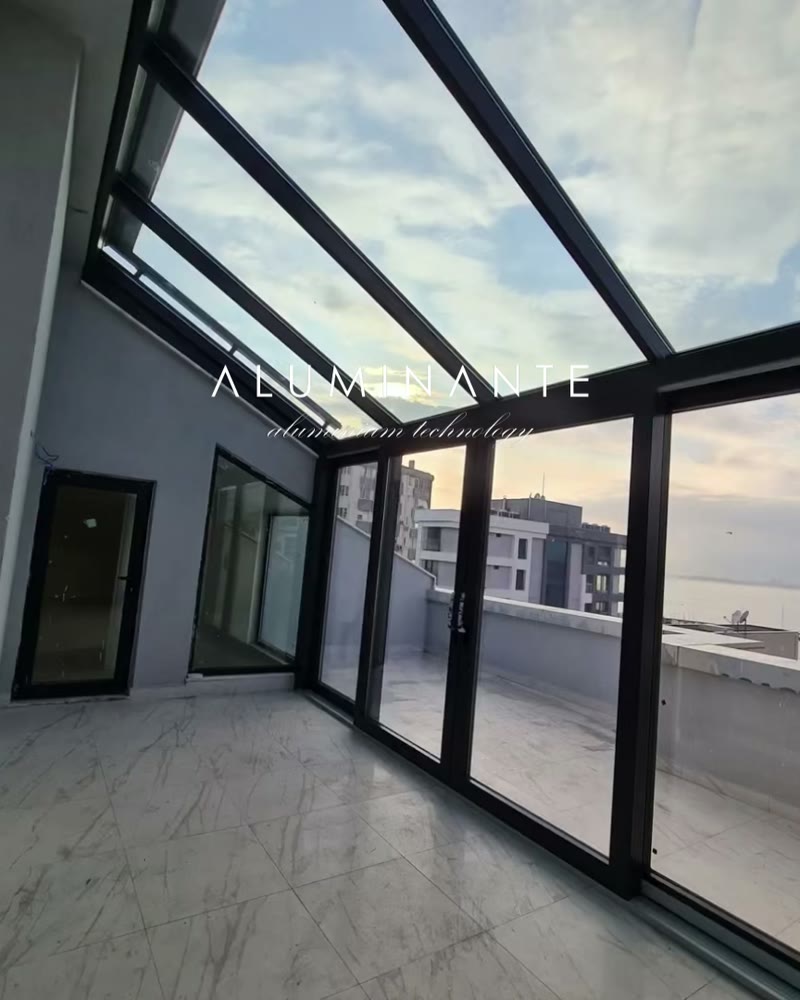 Glass room on a rooftop with a glass roof and floor-to-ceiling sliding doors
