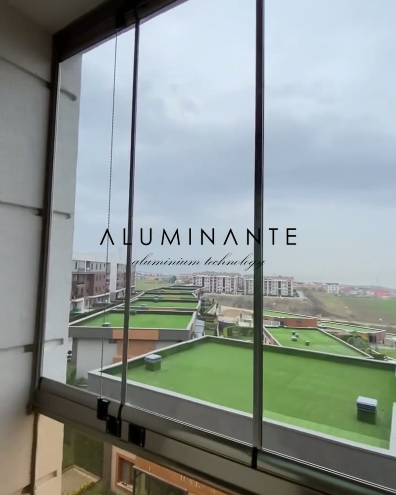 Floor-to-ceiling frameless glazing with a view over green rooftops