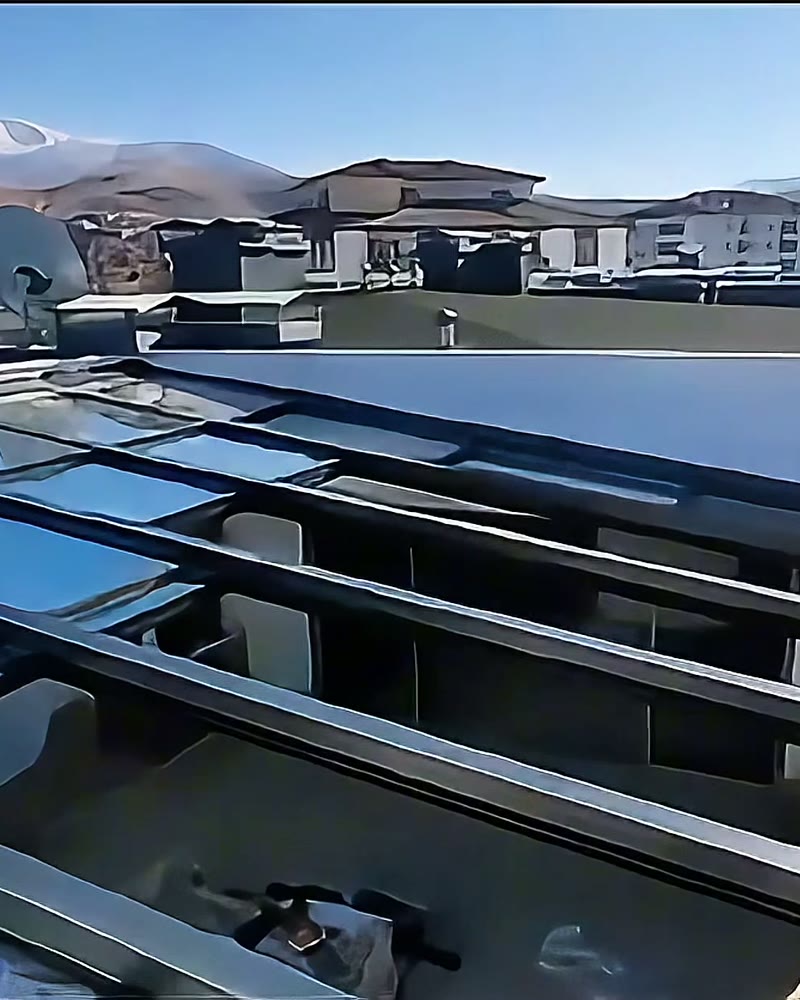 Automatic glass roof partly open on a rooftop with mountains behind