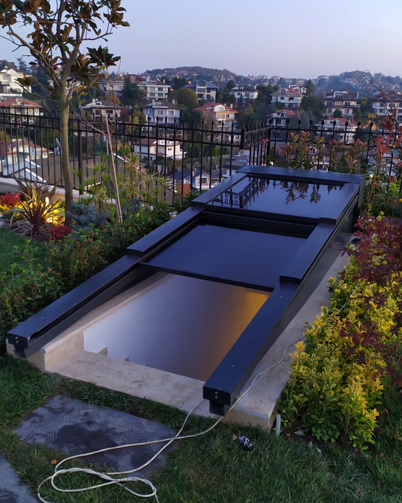 Opening glass skylight set into a garden roof among plants