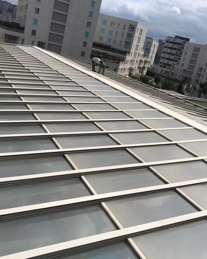 Long automatic glass roof on a building with apartment blocks behind