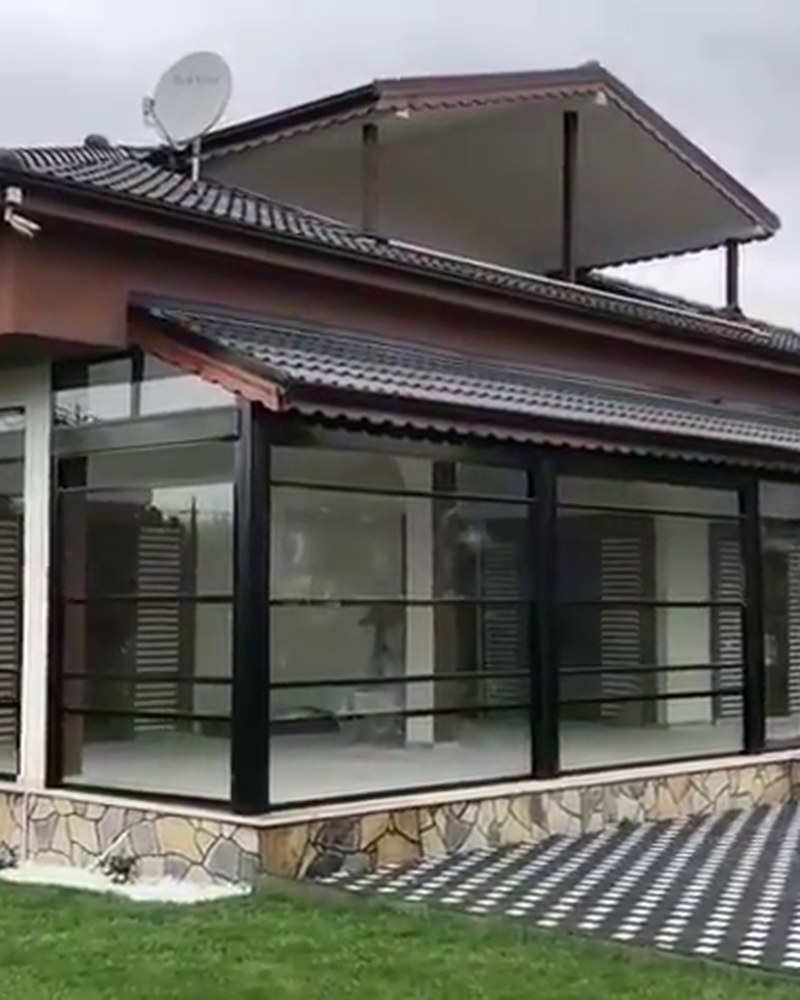 House extension enclosed with black-framed guillotine glass under a tiled roof