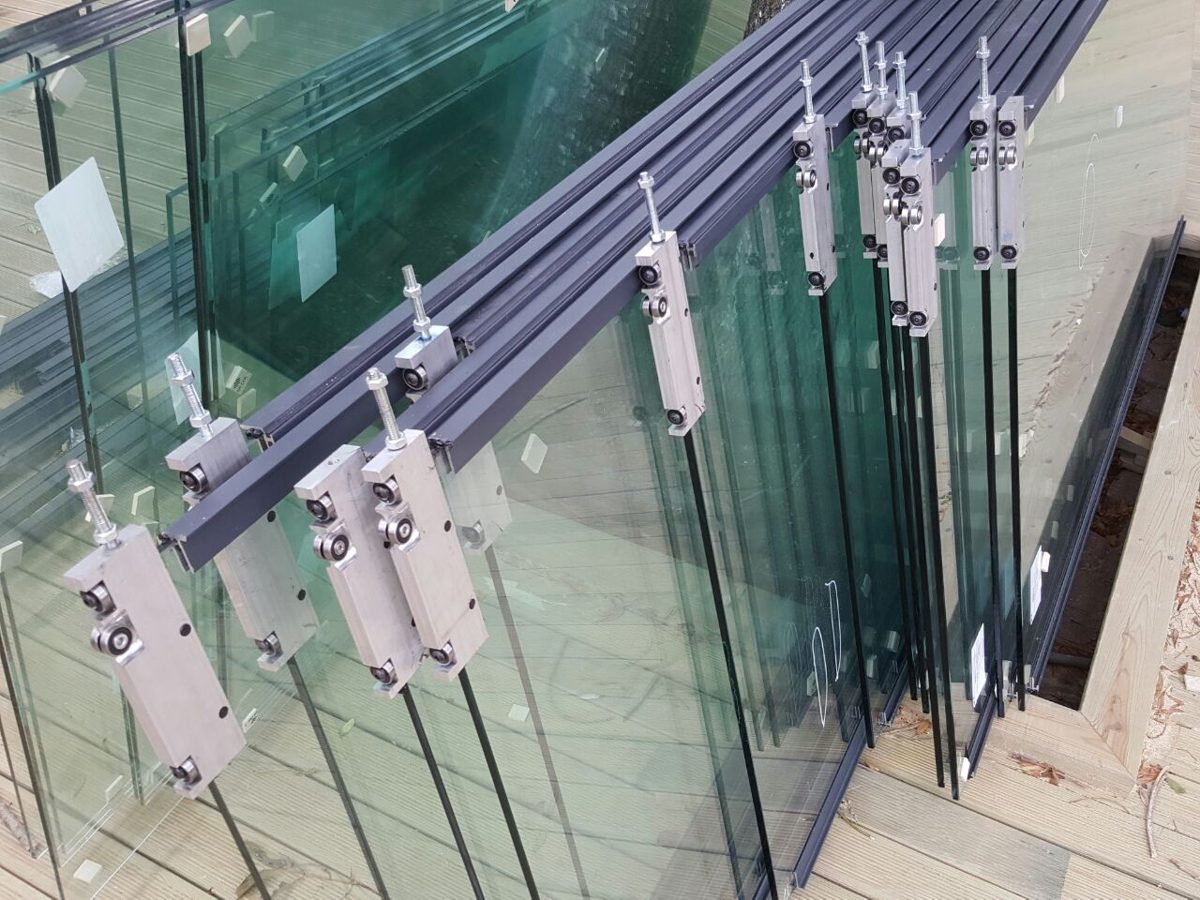 Glass panels with top rollers and aluminum tracks ready for installation