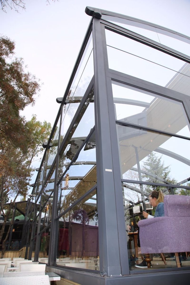 Finished glass enclosure with a retractable fabric roof, guests seated inside